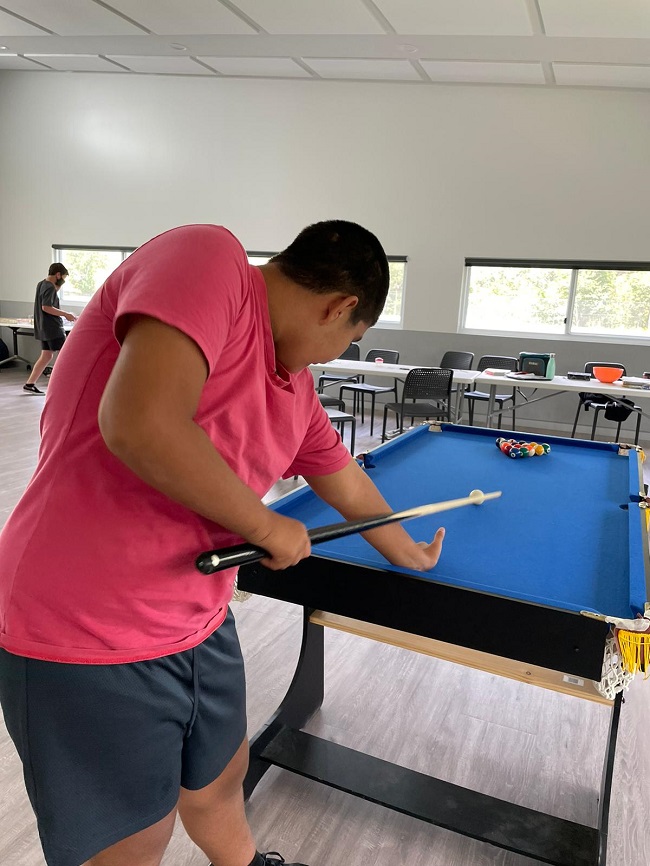 A participant playing pool at a community centre