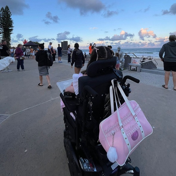 A wheelchair user enjoys an evening outing along a beachfront path